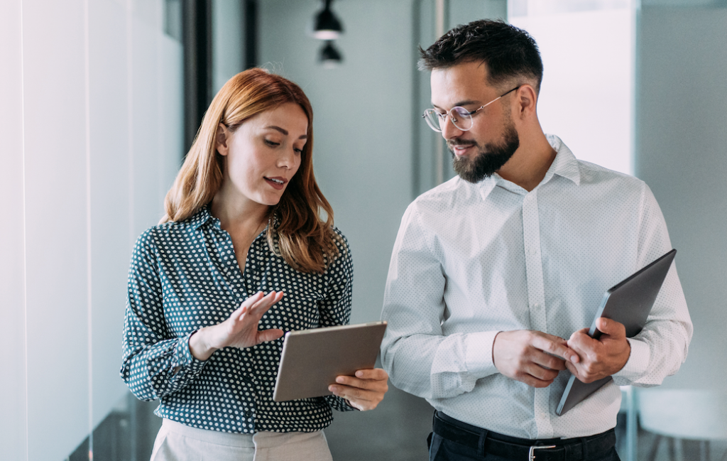A woman and a man talking while holding portable table devices.